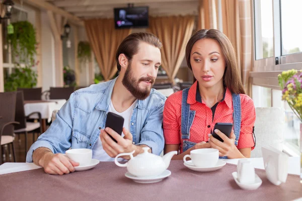 Pretty man and woman are using telephones is cafeteria