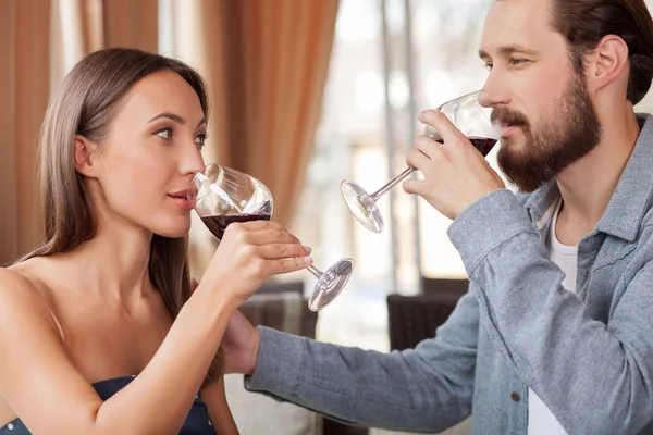 Beautiful loving couple is enjoying red drink in restaurant