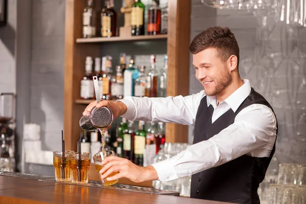 Attractive male barman is making cocktail in bar