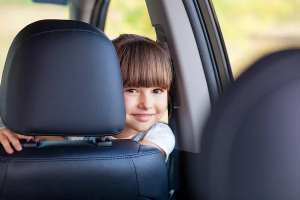 Cheerful small female child is making fun in vehicle