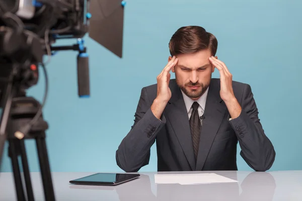 Professional male newscaster feels pain in his head