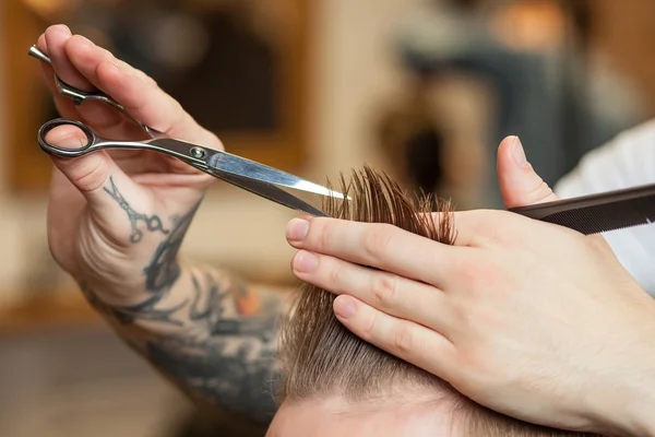 Skillful male barber is serving his customer