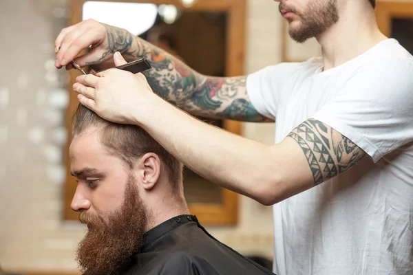 Skillful male barber is serving his customer