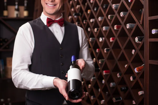 Cheerful winehouse worker is presenting elegant beverage