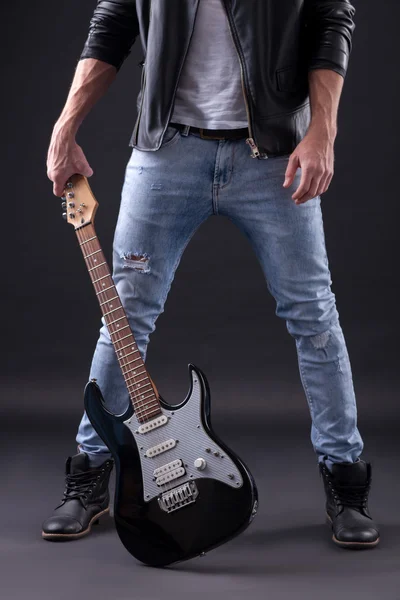 Cheerful young guitarist is preparing for performance