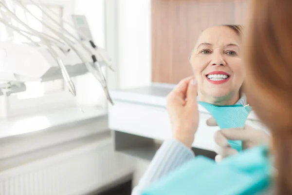 Cheerful mature lady is checking work of orthodontist