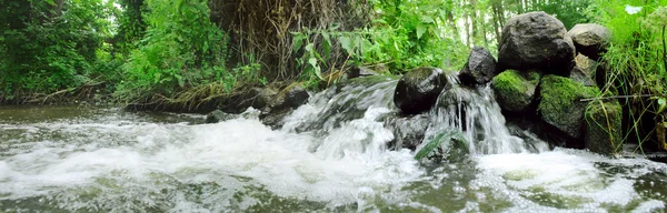 Panoramic image of the forest waterfall in the summer
