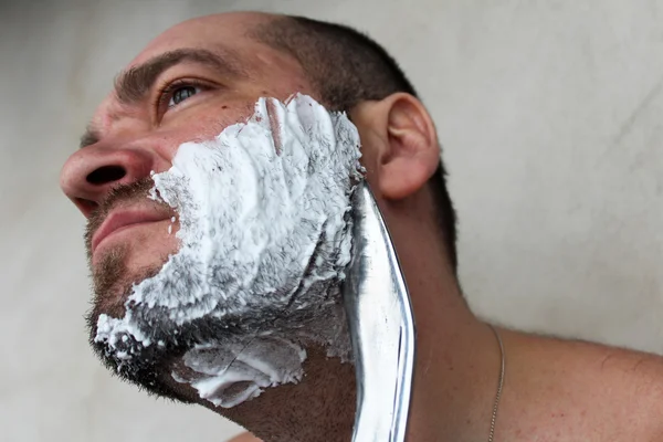 Man shaves his beard with a knife