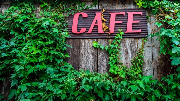 Red cafe sign on wooden wall