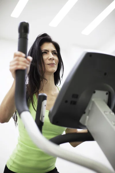 Sporty woman exercising with elliptical machine