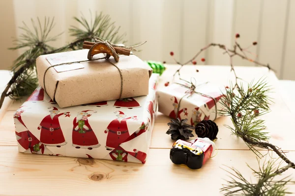 New Year gift packaging hand made with cinnamon stick on a background of pine cones, pine branches and Christmas decorations on a natural wooden background