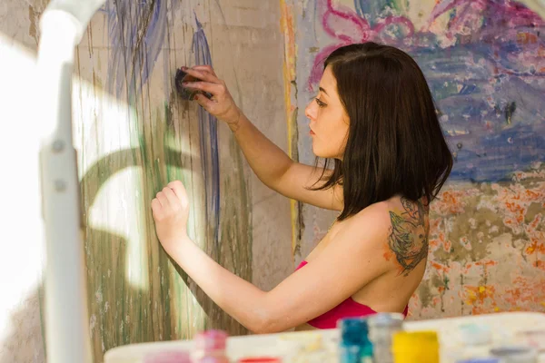 Beautiful girl artist paints on the wall