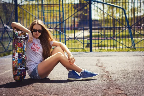 Cute girl in shorts with a skateboard on the Playground