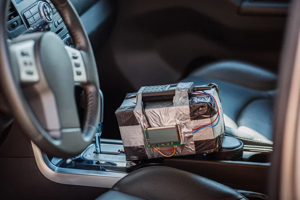 Black bomb with radio control and digital countdown timer lies in the car