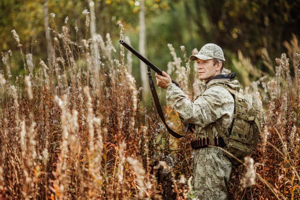 Man hunter with shotgun in forest