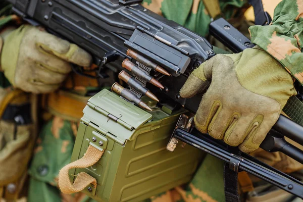 Soldier in gloves holding automatic machine gun