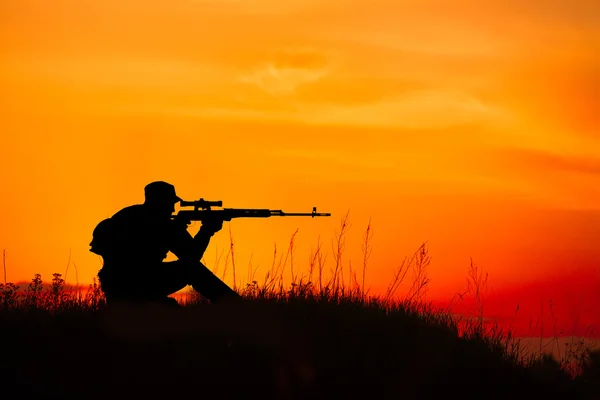 Silhouette of military sniper with sniper rifle at sunset. shot,