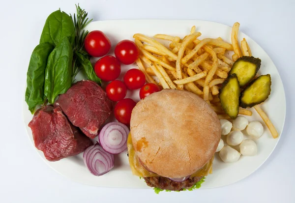 Fresh burger in plate with vegetables and french fries.Big hamburger. Ingredients for hamburgers. Top view