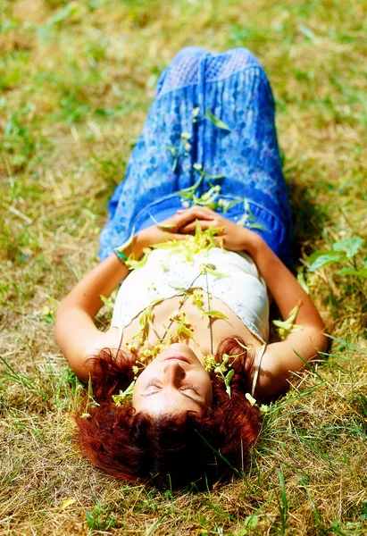 Dreaming girl lying on meadow sprinkled with linden tree flowers.