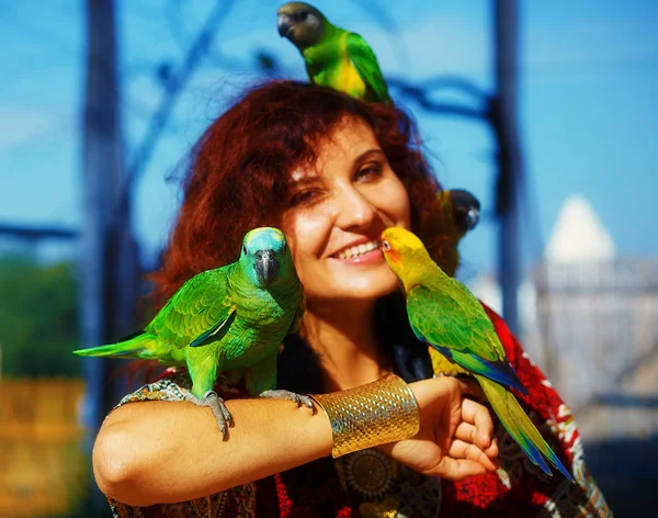 Young woman in ornamental dress and beautiful gold jewelry with a color parrots