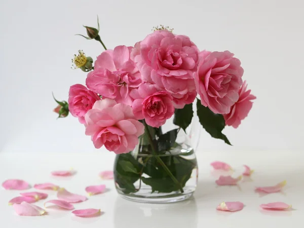 Bouquet of pink roses in a vase. Floral still life with roses and petals.