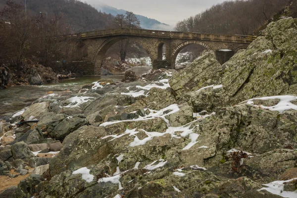 Bridge across river with green waters, snow and ice near Xanthi