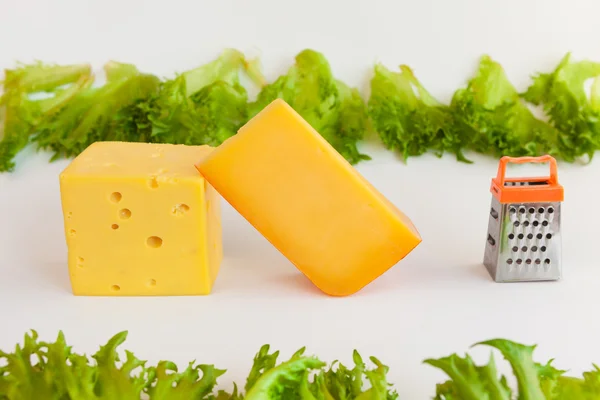 Pieces of cheeses, metal grate for preparing  grated cheese and leaves of frillis