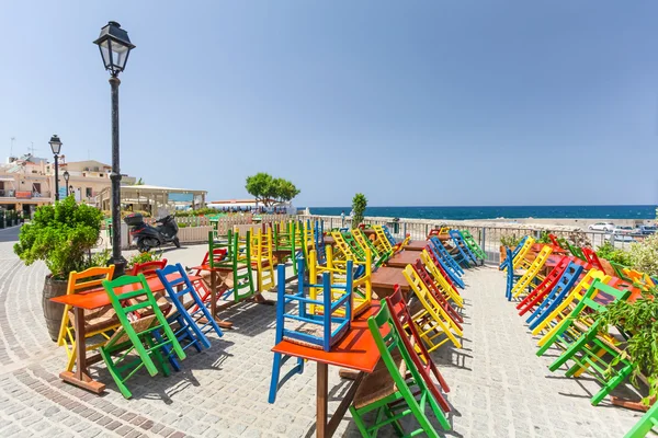 Rethymno, Island Crete, Greece, - July 1, 2016: View of the cafe with color chairs which is located near the embankment of Mediterranean Sea