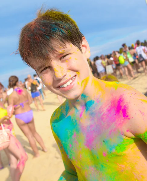 Cute young boy with colored face, beach party