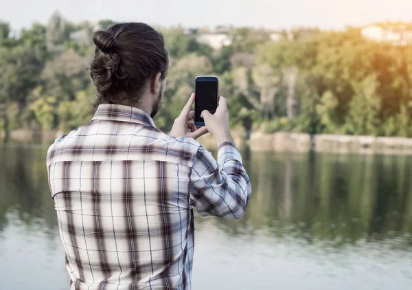 Young guy photographing landscape with smartphone