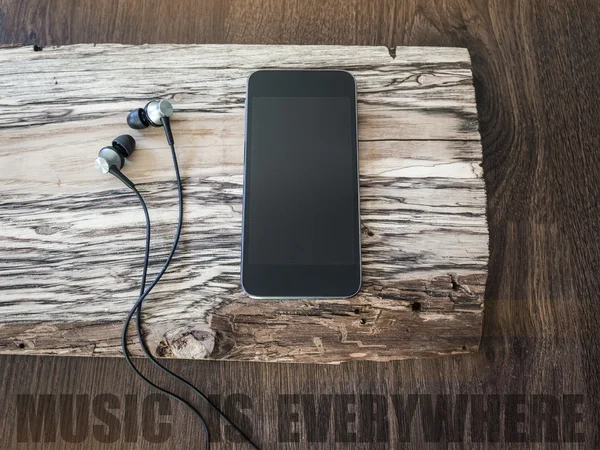 Music player with headphones on a piece of wood. Music is everywhere