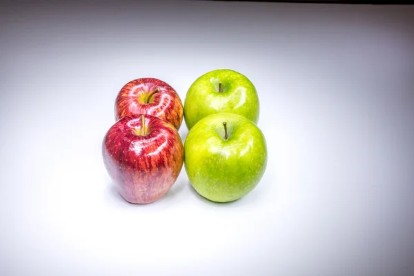 Four red and green apples in square composition painted with light
