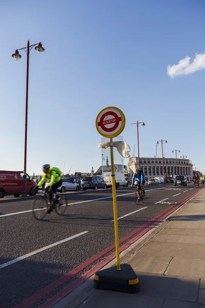LONDON, UK - 2016.03.31: Bus Stop sign on the Blackfriars Bridge, cyclists in the background