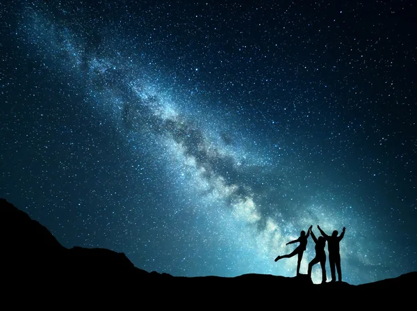 Landscape with Milky Way and silhouette of a happy family