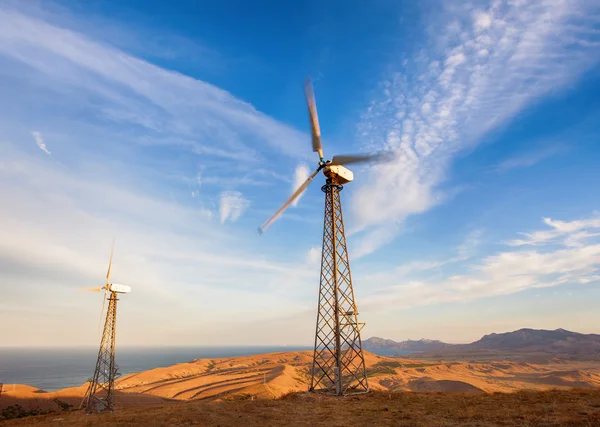 Industrial landscape with wind turbine generating electricity in mountains at sunset.