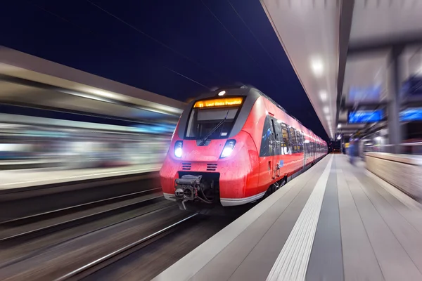 Modern high speed red passenger train moving through railway sta