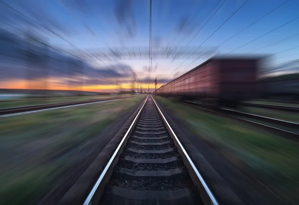 Railway station with cargo wagons in motion blur effect at sunse