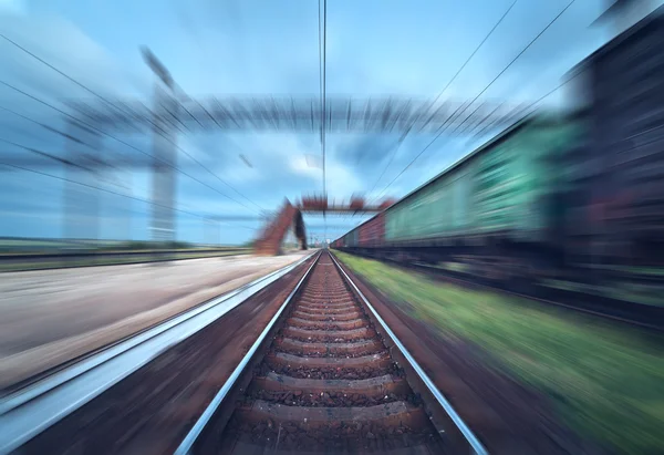 Railway station with cargo wagons in motion blur effect at sunse