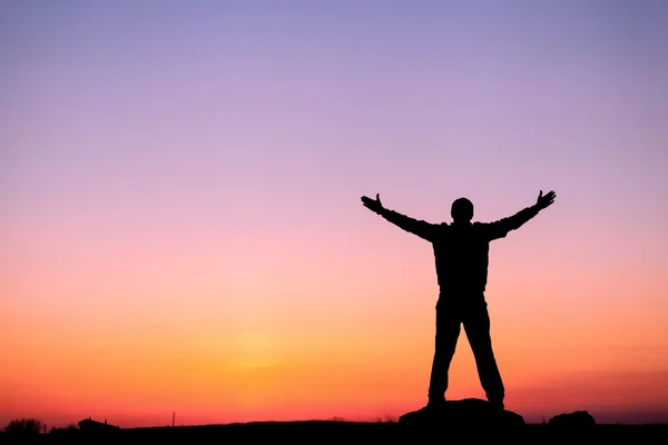 Silhouette of man with arms raised up and beautiful sky