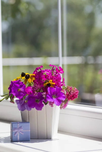 Spring pink flower composition and blue gift box near the window