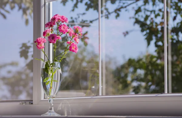 Bouquet of pink roses in glass near window