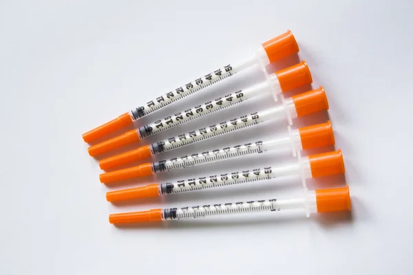 Six insulin syringes on a white background