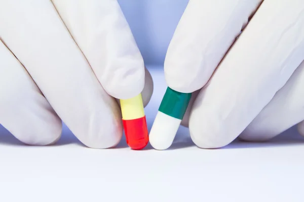 Close-up hand in medical rubber glove holding two different caps