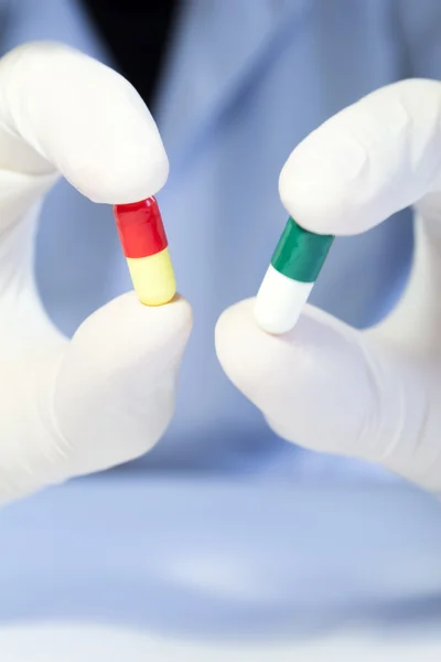 Close-up hand in medical rubber glove holding two different caps