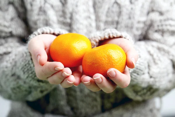Female hands holding  tangerines