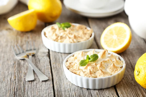 Lemon meringue pie in bowl on grey wooden background