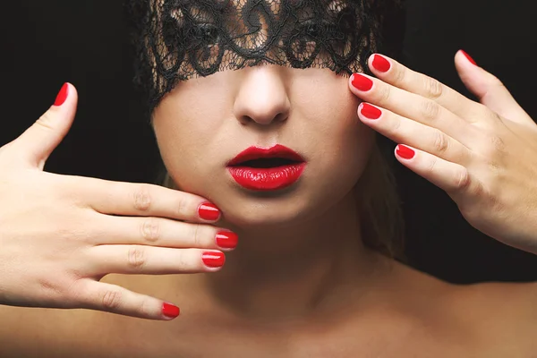 Beautiful model with black lace mask, red lips and manicure