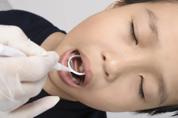 Boy checking tooth by mirror