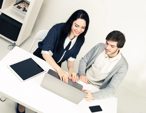 Top view of two young people working together while sitting at minimalistic white office
