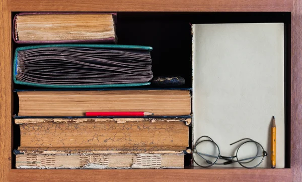 Still life with wooden book shelf, rare antique books, textured pages, pencils, blank paper scroll and retro design glasses. Path to wisdom conceptual image.